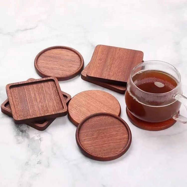 A set of round and square wooden coasters with a cup of tea on one.