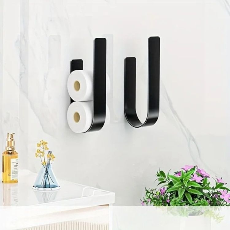 Two black U-shaped toilet paper racks, one holding two rolls, on a marble-patterned wall.
