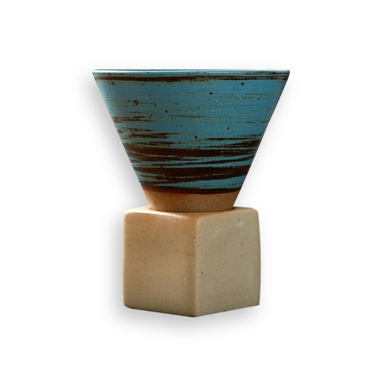 Blue, textured ceramic cone coffee cup on a square wooden base.