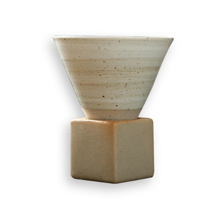 White, speckled ceramic cone coffee cup on a square wooden base.