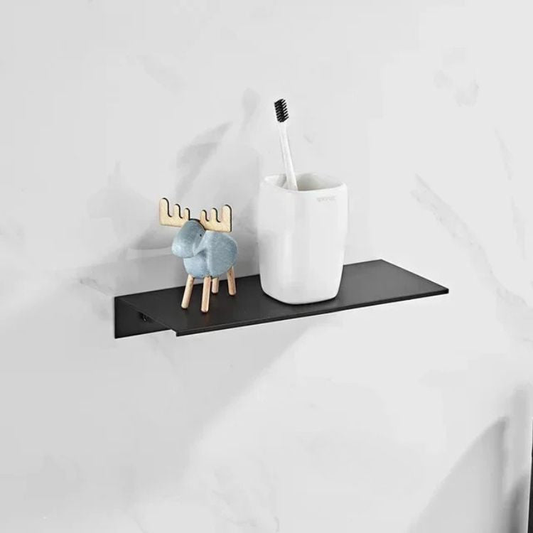Black floating wall shelf with white soap dispensers and glass accessories.