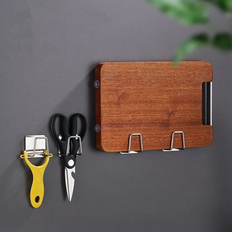 Wall-mounted dual sink sponge rack used for hanging kitchen tools and a cutting board.