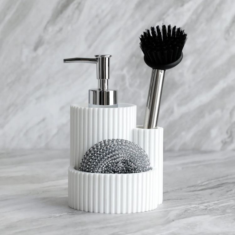 White ribbed kitchen detergent dispenser set with metal scrubber and dish brush.