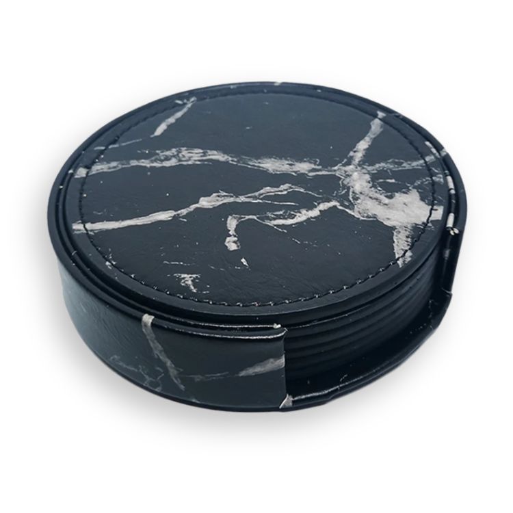 Close-up of black marble-style drink coasters neatly stacked in a holder.