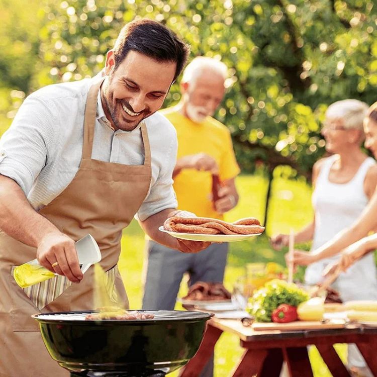 Man grilling outdoors while using an oil sprayer bottle at a barbecue.