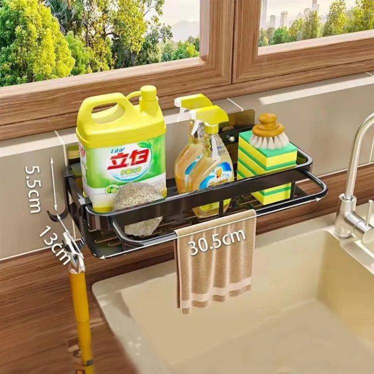 Sink drain rack with bottles and towel by window.