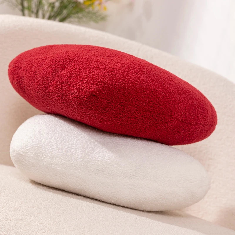 Side view of a red and white Heart Shape Throw Pillow stacked on a cream chair.