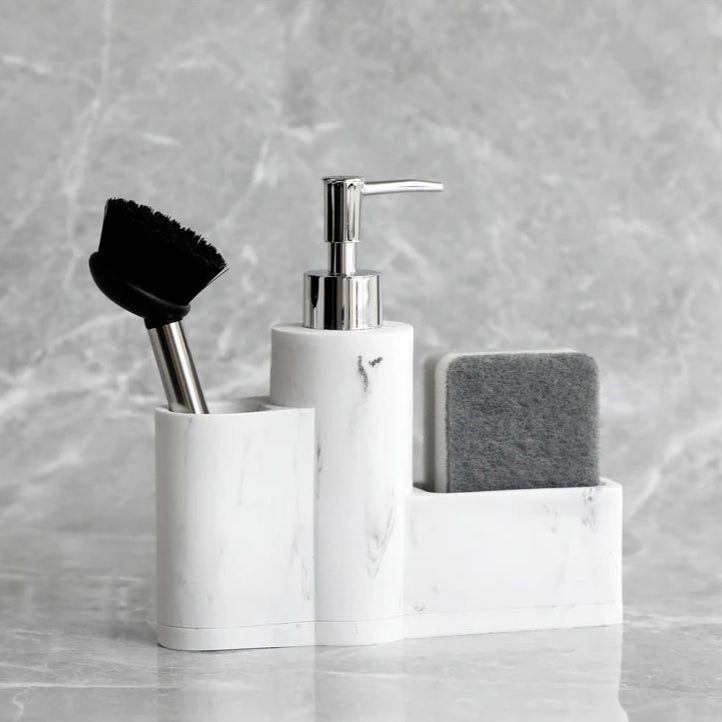 White marble dish soap dispenser with brush and grey sponge.