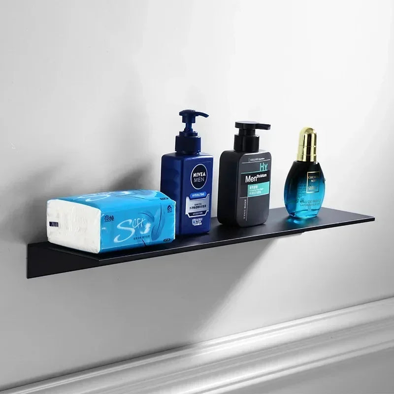 Black floating wall shelf mounted on white wall holding soap and skincare items.