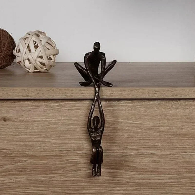 Sculpture ornament of climbing figures displayed on a wooden surface.