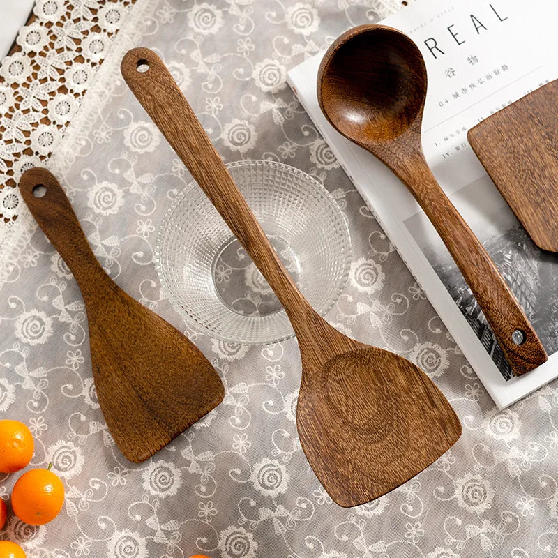 Wooden kitchen utensils with a ladle and flat spoons placed with a spoon rest.