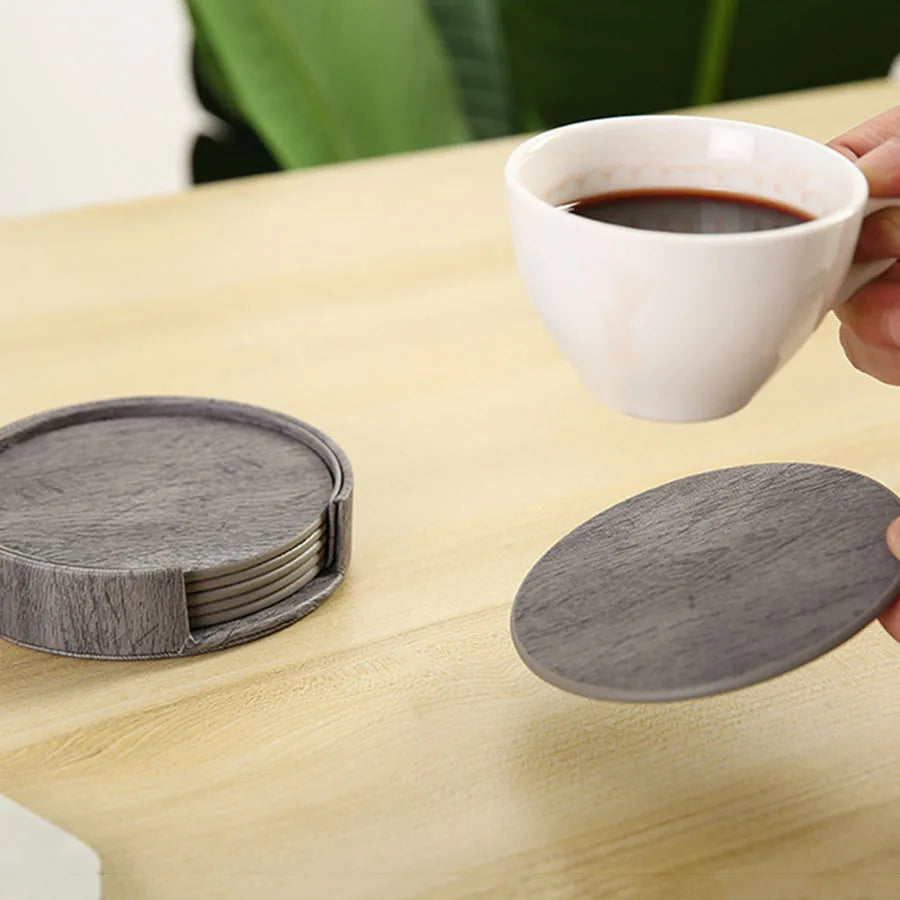 Hand holding gray coasters tea near its holder.