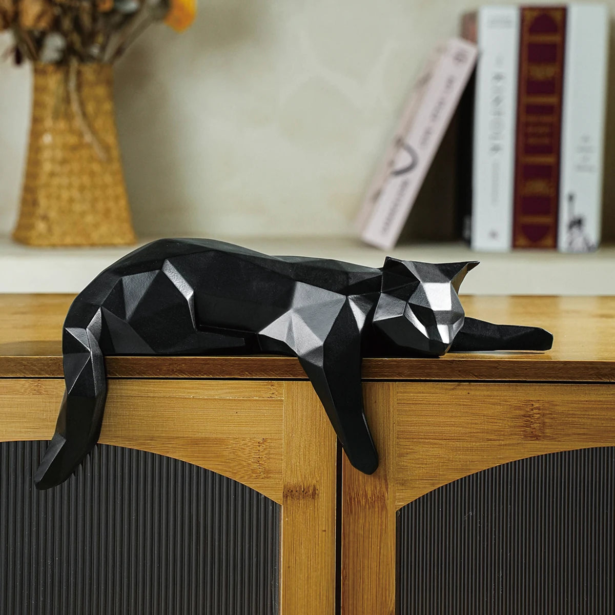 Black geometric decor cats posed on cabinet edge.