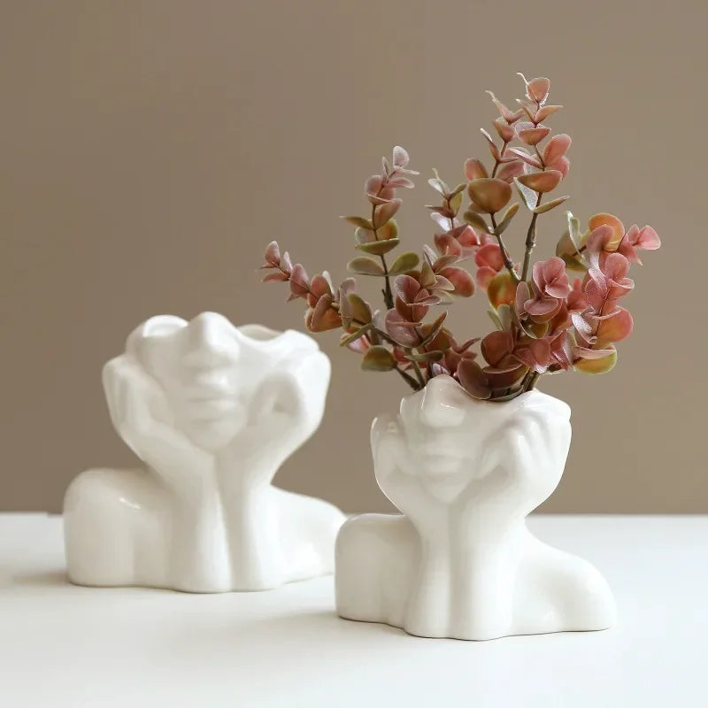 White body shape vase beside a smaller one on a brown surface.