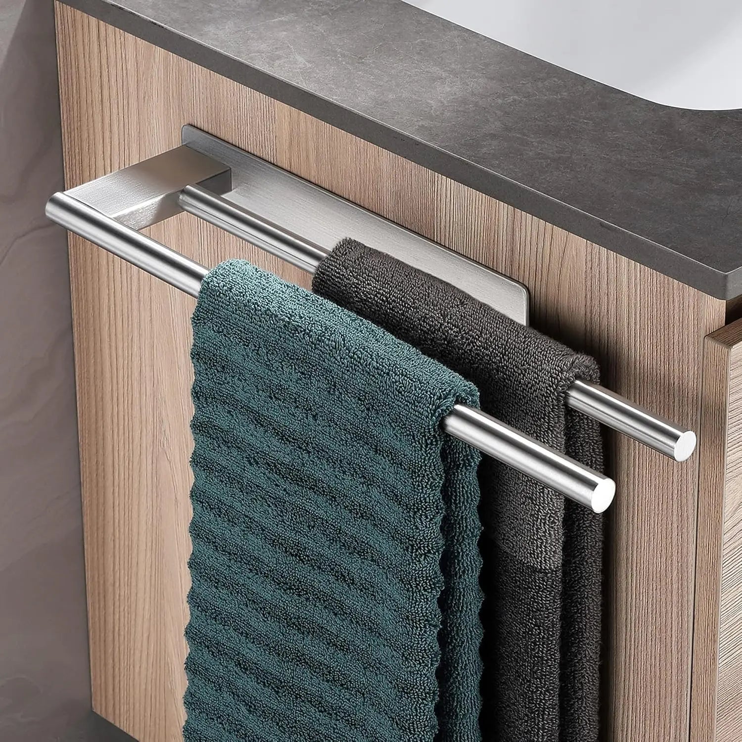 Double silver adhesive towel bar attached to cabinet, holding green and grey towels.