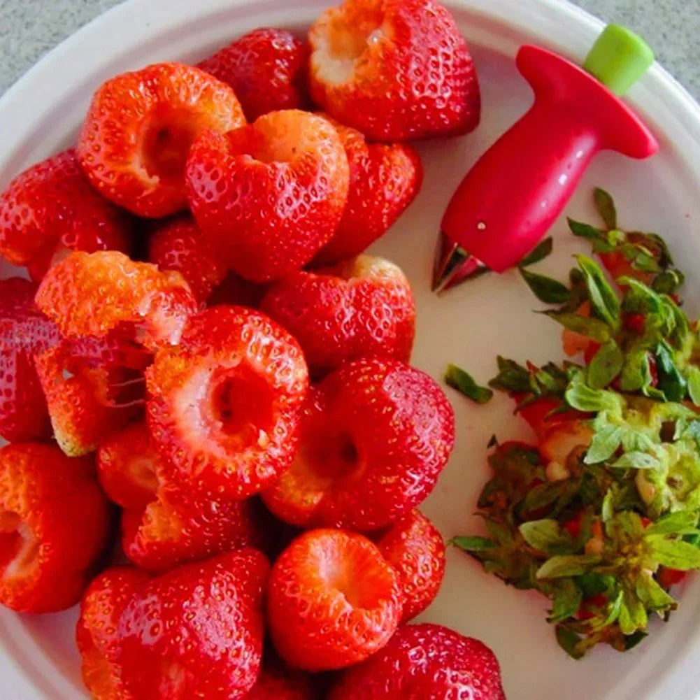 Fruit corer surrounded by freshly cored strawberries.