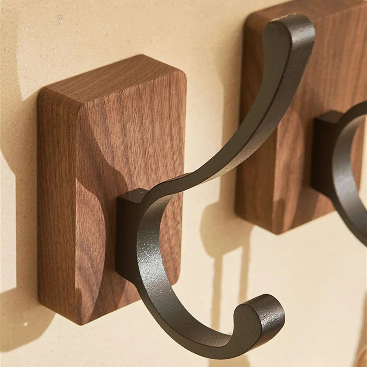 Close-up of two wood hooks with curved dark metal arms.