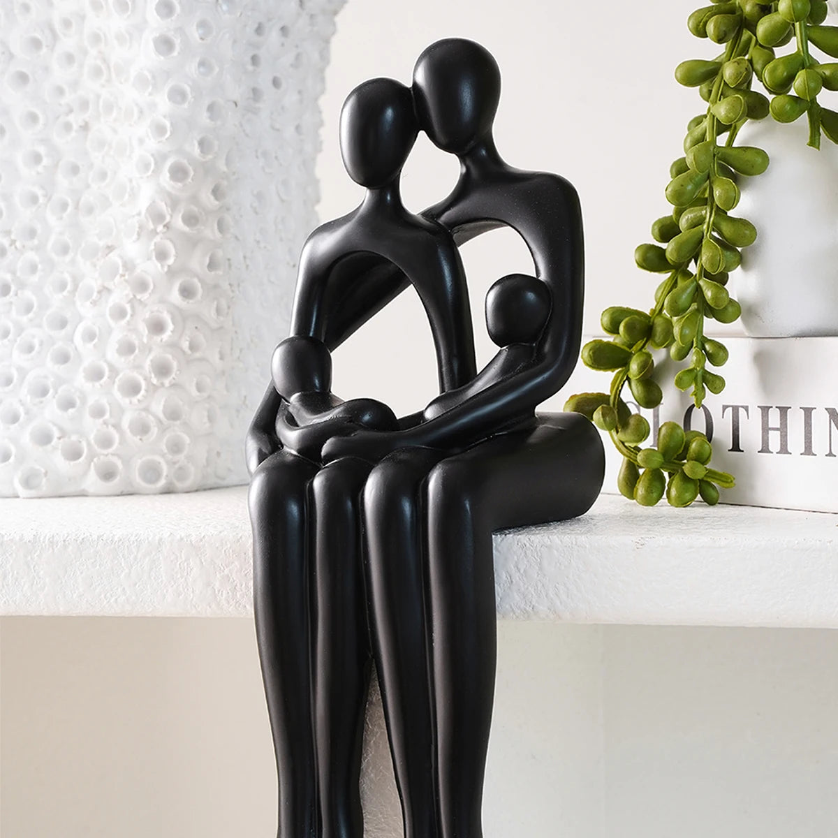 Black desk statue of a couple in a sitting embrace on a shelf.