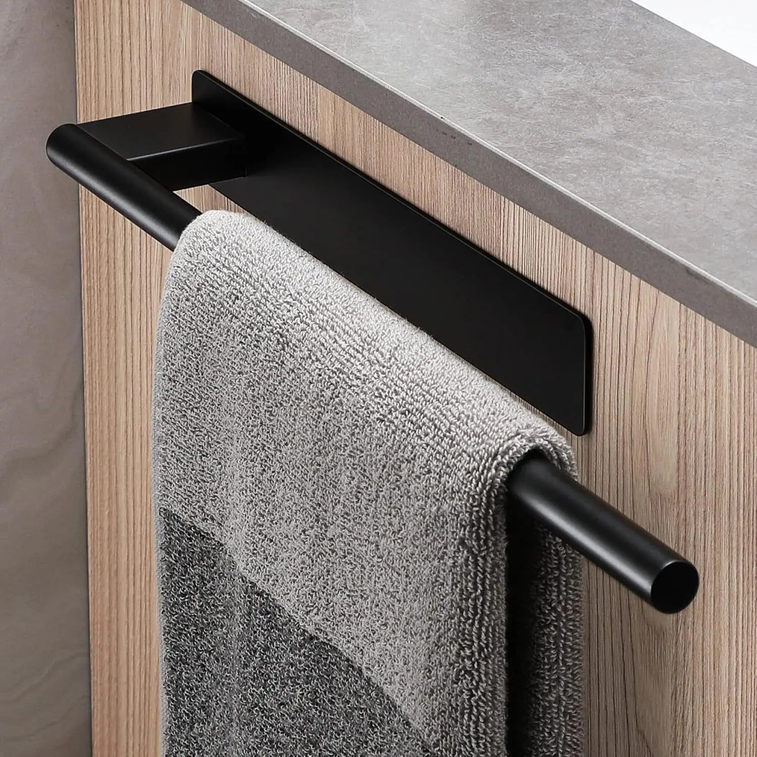 Single black adhesive towel bar fixed to a cabinet, holding a grey towel.