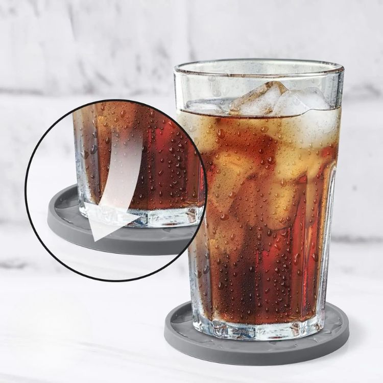 A glass of iced cola on a grey silicone coaster