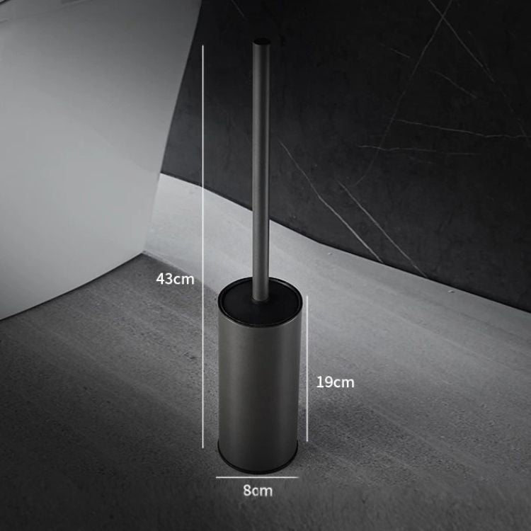 Freestanding chrome toilet brush holder placed beside a modern toilet.