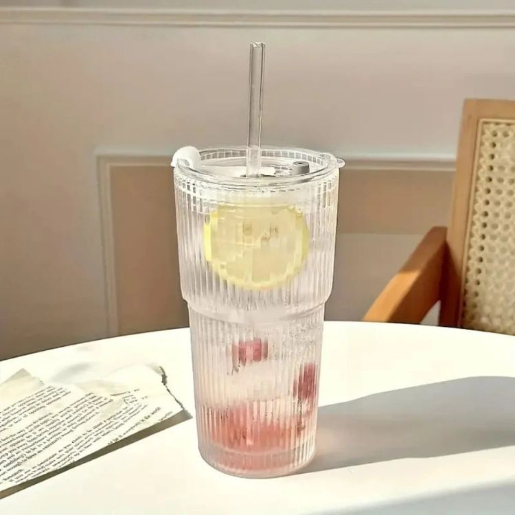 Glass cup with lid on table with lemon water.