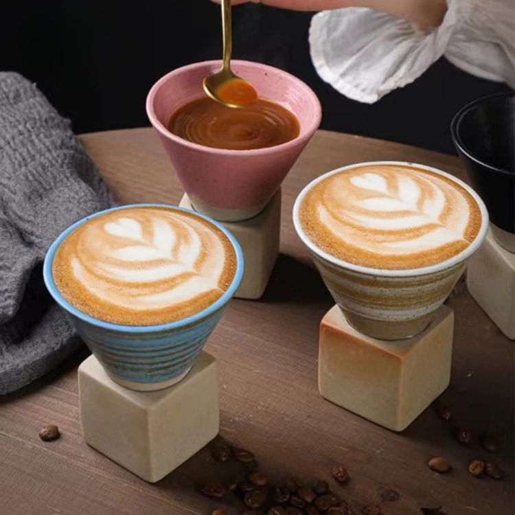 Three ceramic coffee cups on wooden stands