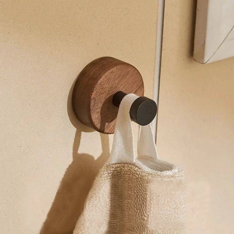 A round wood hook with a black peg holding a white, folded strap.