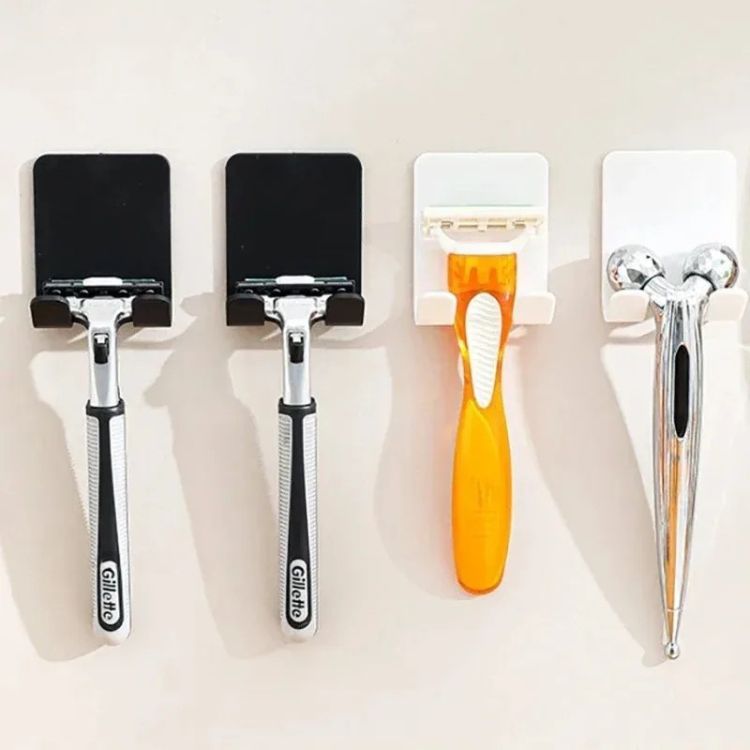 A silver-colored razor holder with a suction cup, holding a razor on a glass surface.