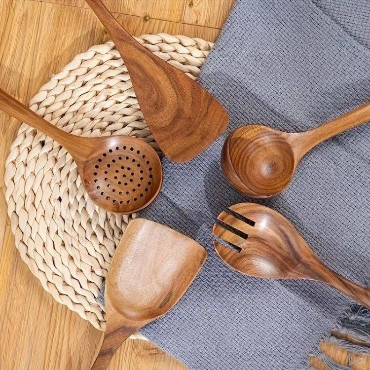 Wooden spoons for cooking placed neatly on a wooden table beside seasoning bowls.