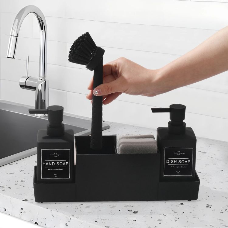 Hand grabbing brush from sink caddy by the sink.
