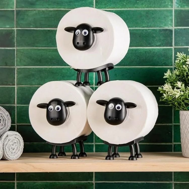 Sheep toilet paper holder displayed against green tile wall, holding two rolls.