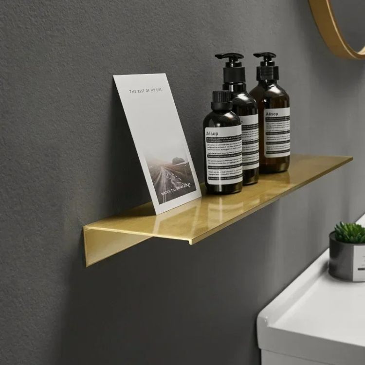 Brushed floating wall shelf displaying shampoo bottles and a photo frame.
