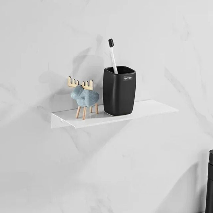 White floating wall shelf above toilet with black bottles and decor.