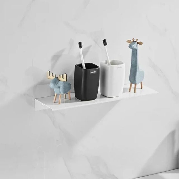 White floating wall shelf with minimal decor above toilet.