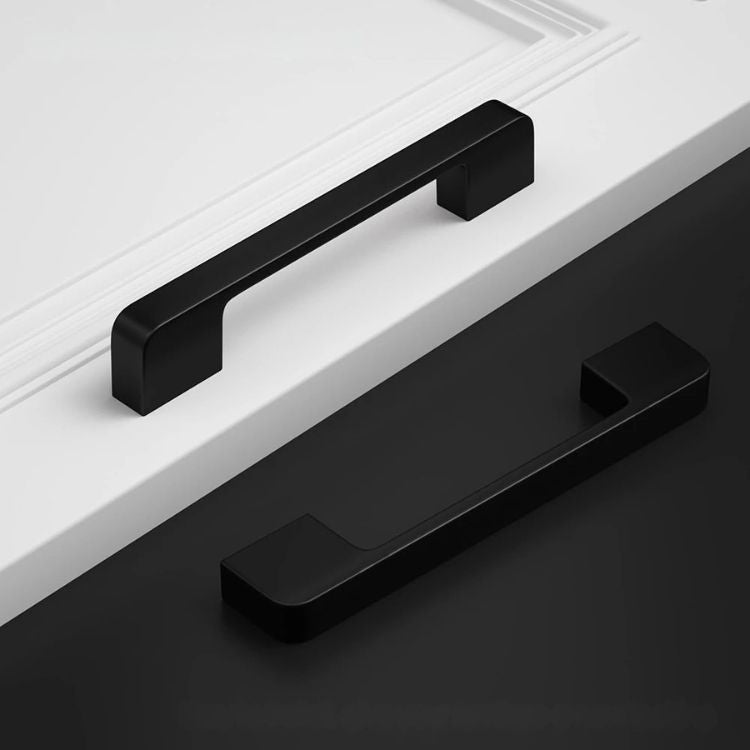 Black kitchen cabinet knobs mounted on white and black drawers.