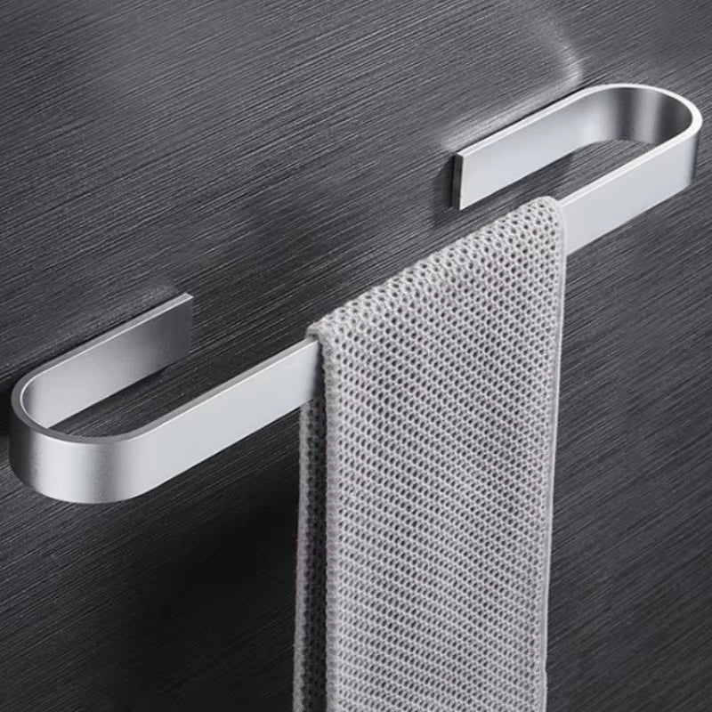 Wall-mounted silver towel rail rack holding a grey hand towel on a dark surface.