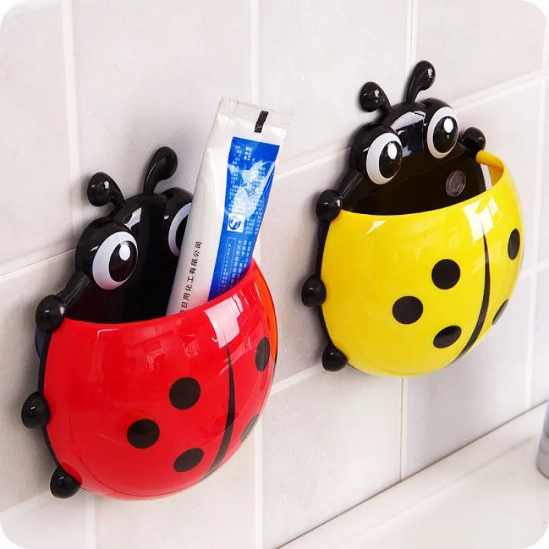 A red ladybug toothpaste holder with toothpaste in it, next to a yellow one.