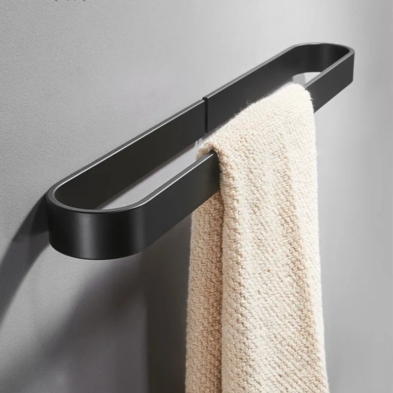 Black metal kitchen towel rack mounted on a wall, holding a beige towel.