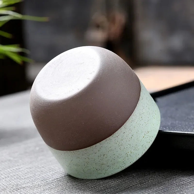 Close-up of an upside-down Kung Fu Teacup in green and brown ceramic, showing its smooth, minimalist finish and rounded base.