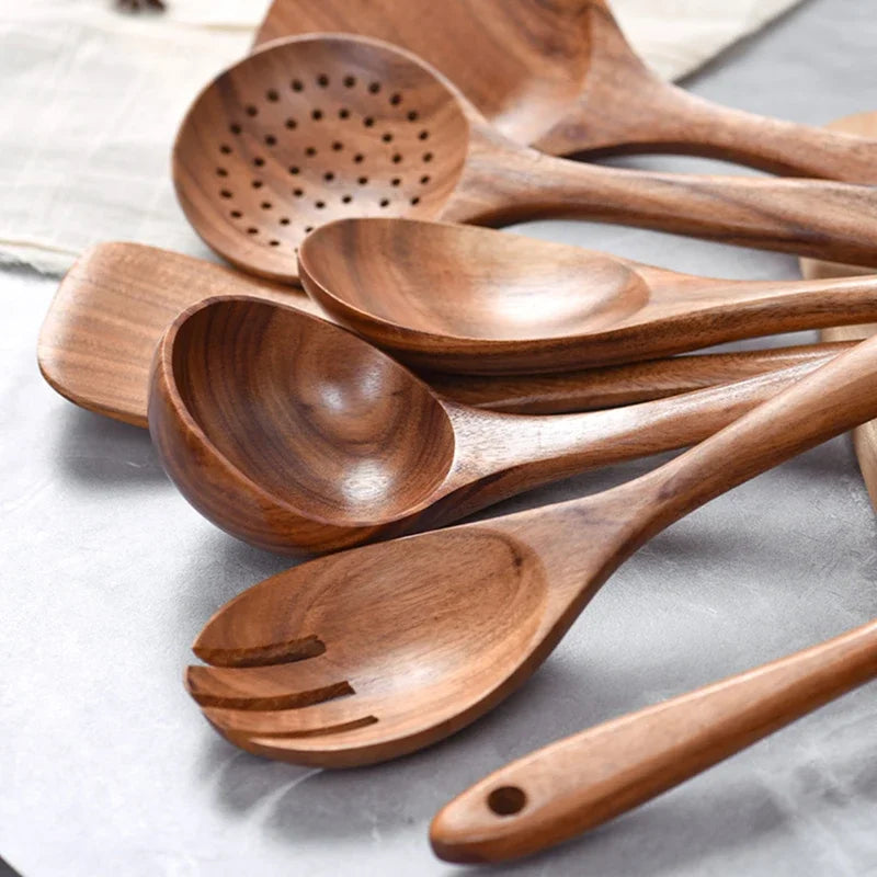 Wooden kitchenware set stacked together on a grey surface.