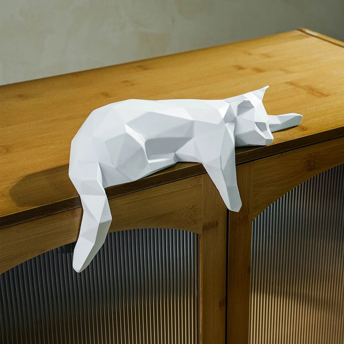 White geometric decor cat draped over cabinet corner.