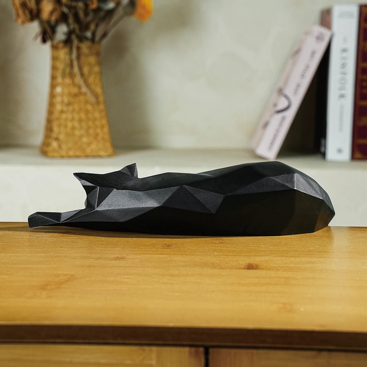 Close-up of black geometric decor cat curled up on wooden surface.