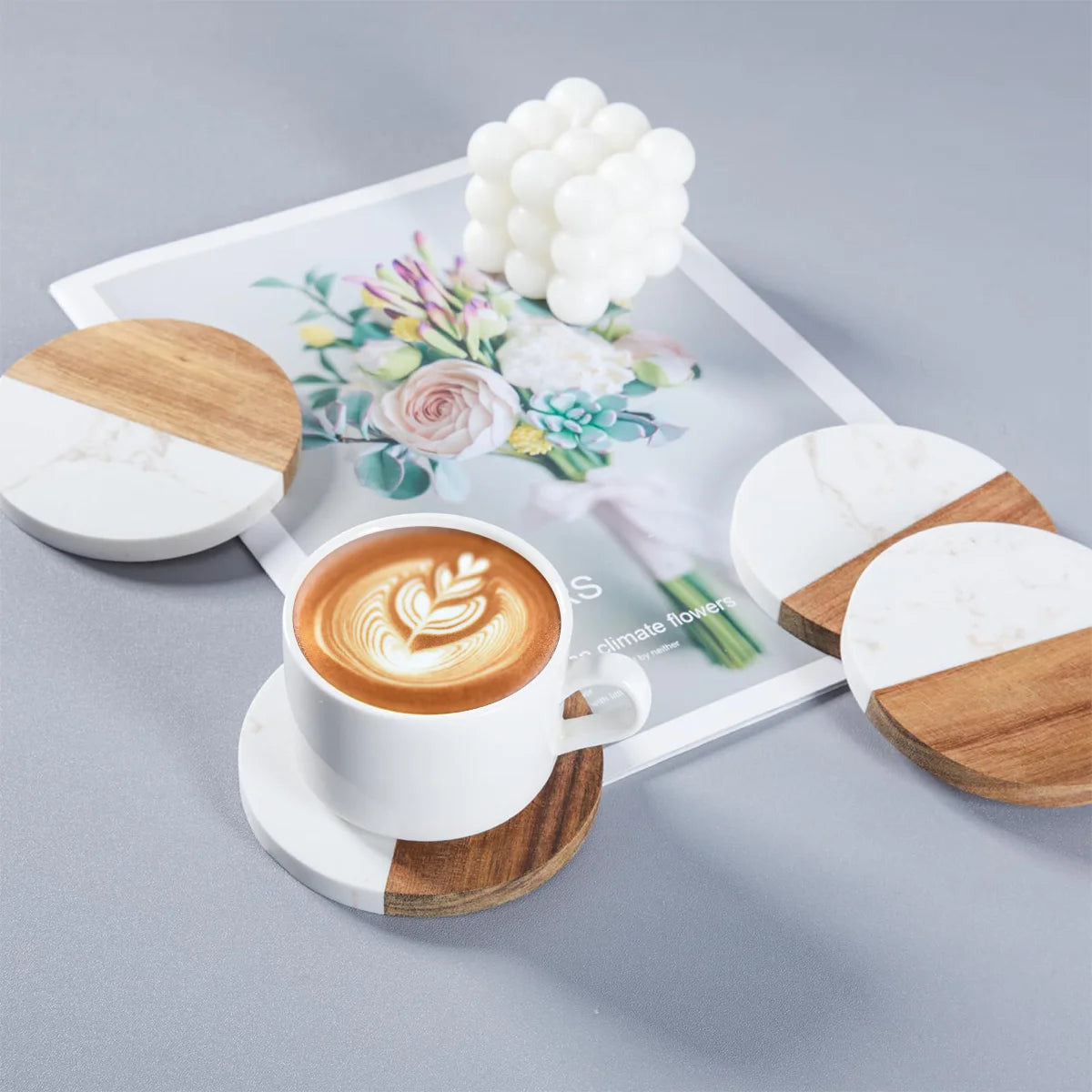 Coffee coasters with a cup of latte art coffee on top, displayed with decorative items on a tray.