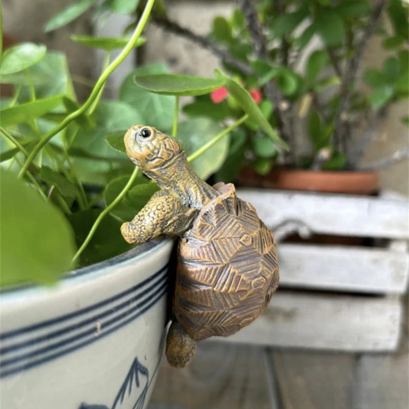 Turtle-shaped garden sculpture sitting on the edge of a striped planter with soil and plants.