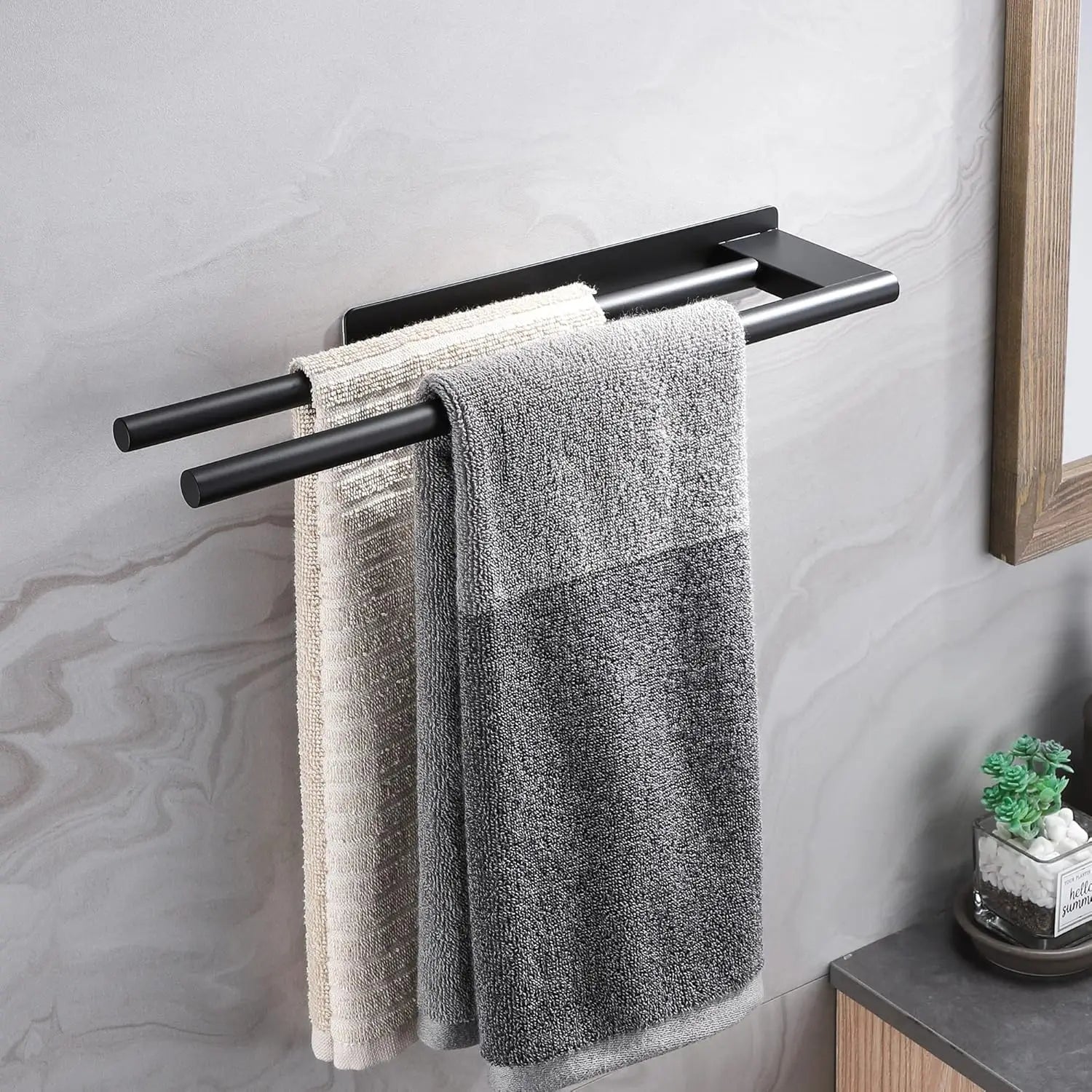 Wall-mounted black adhesive towel bar with two towels hanging neatly.