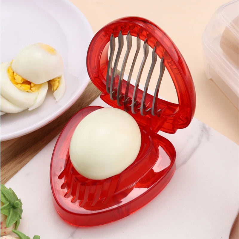 Red, heart-shaped strawberry slicer with sliced and whole strawberries.