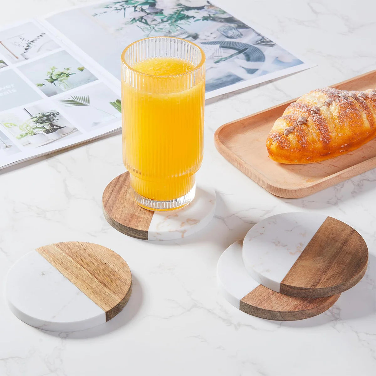 Round coffee coasters with marble and wood design, one holding a glass of orange juice