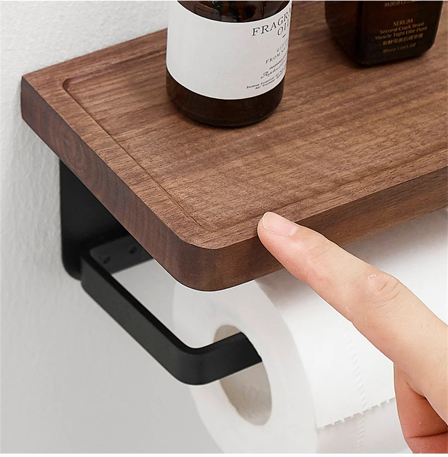 A wooden toilet paper holder attached to a tiled wall, with a small plant on its shelf.