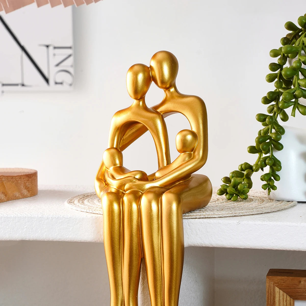 Golden couple hugging desk statue sitting on a white shelf edge.